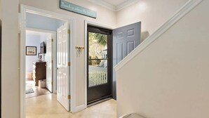 A hallway with a closed door, a sign above the door, and a staircase to the right.