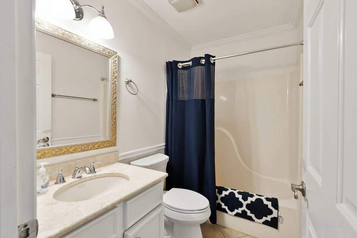 A bathroom with a white sink, a toilet, and a shower with a blue curtain.