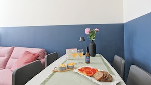 Une table à manger avec un repas, une bouteille et un vase rempli de fleurs.