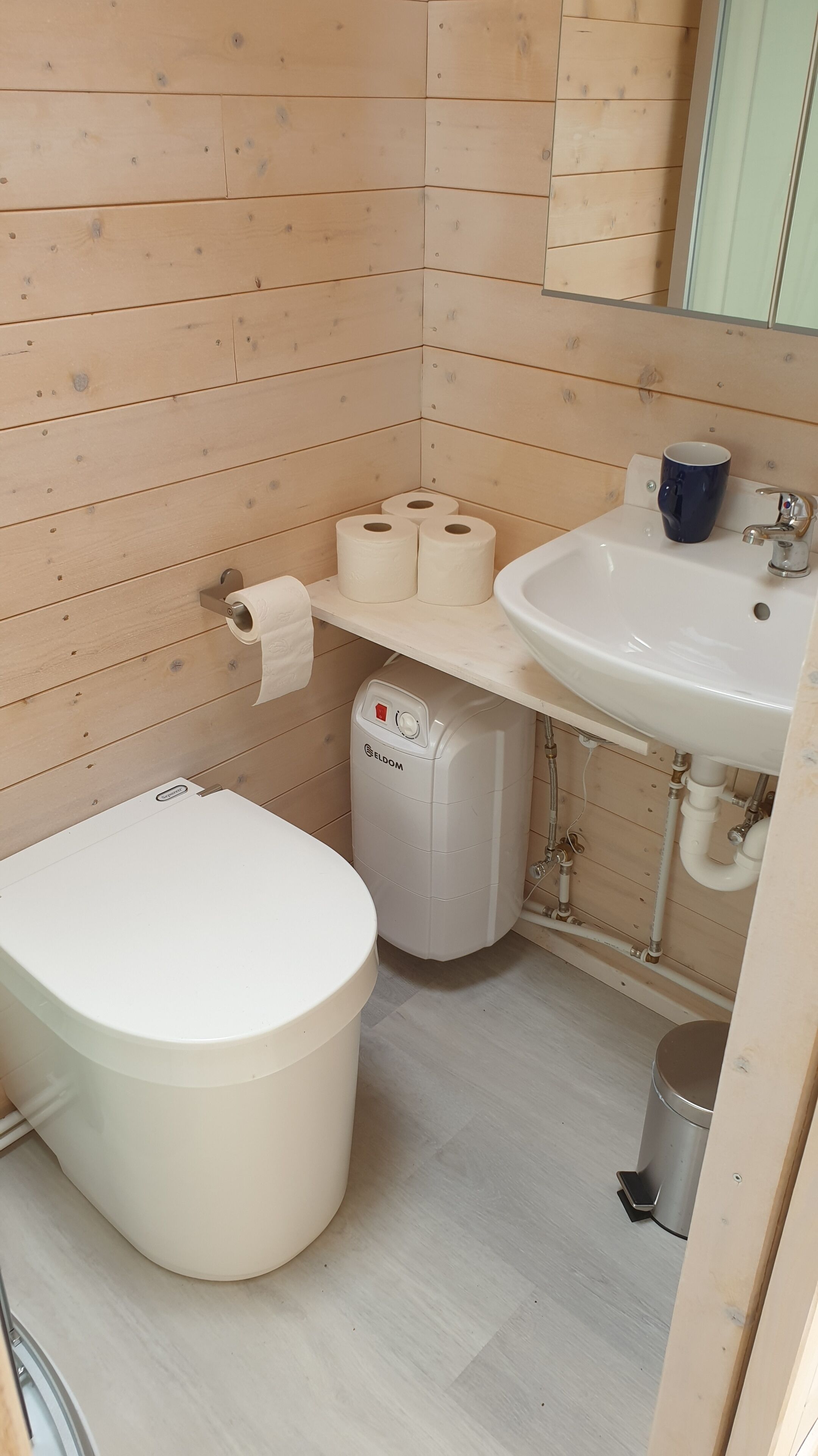 Un bagno piccolo e compatto, con il water, un lavandino e un cestino.