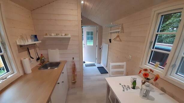 Une cuisine compacte avec des meubles en bois, un évier et un coin repas comprenant une table et des chaises.