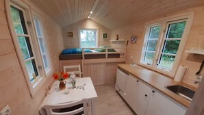 Une petite cabine comprenant un coin cuisine, une table à manger et un lit superposé.