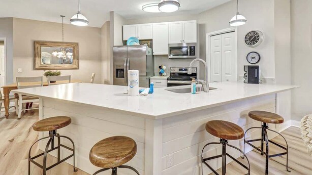 Una cocina moderna con armarios blancos, electrodomésticos de acero inoxidable y una isla grande con taburetes de bar.