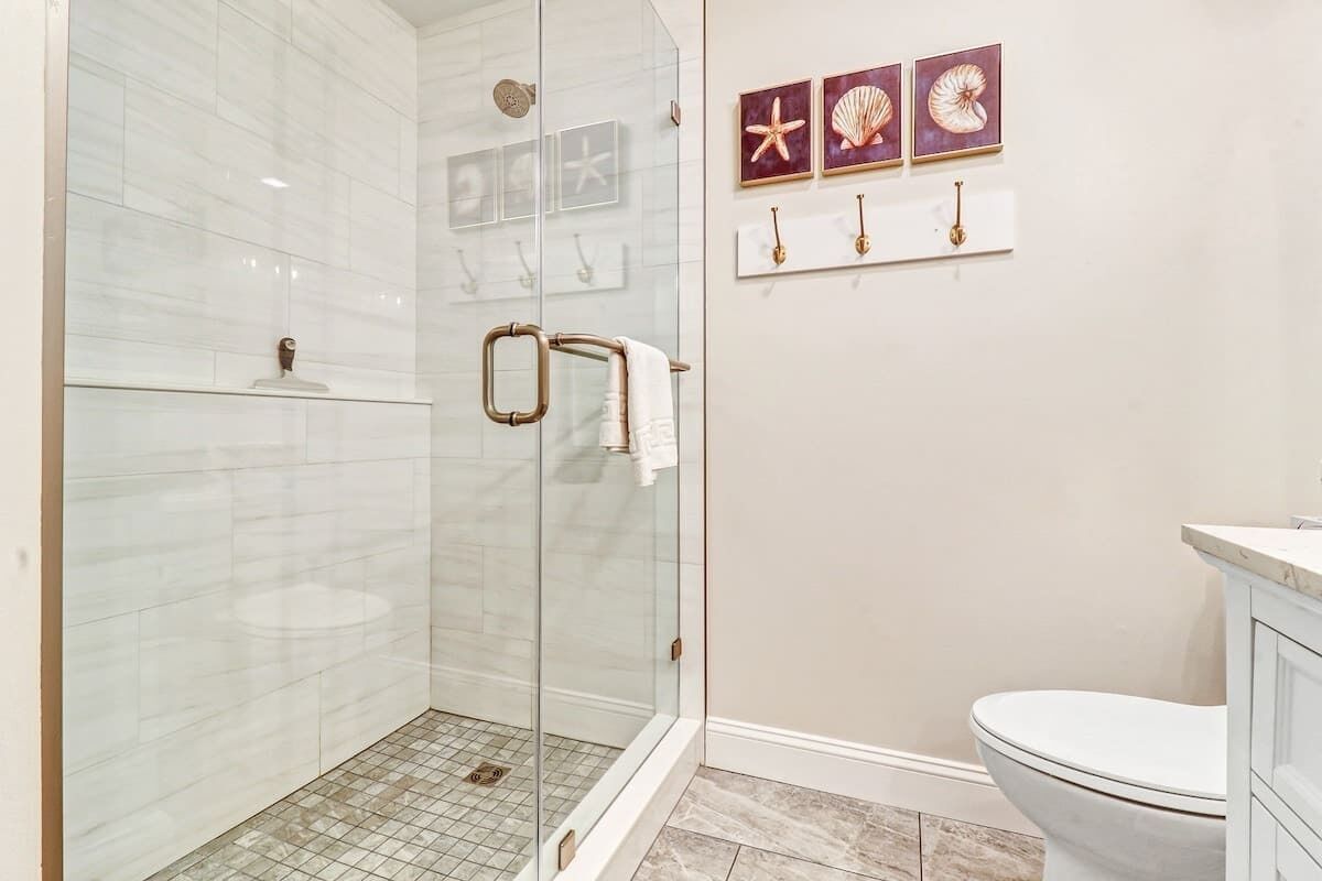Une salle de bain avec une douche à parois de verre, des toilettes et un meuble-lavabo avec un évier.