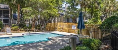 A swimming pool surrounded by lush greenery and a wooden fence.