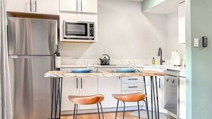 A modern kitchen with a stainless steel refrigerator, a microwave, and a wooden island with bar stools. - Lover's Landing | Walk to Gondola | Rooftop Hot Tub #026194 (Vail)