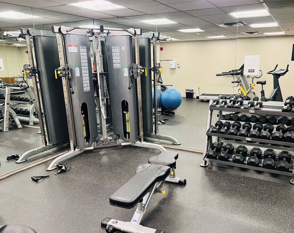 Un gimnasio con máquinas de pesas, mancuernas y pelotas de ejercicio.