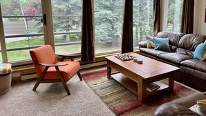 Un salon avec un canapé en cuir marron, une table basse en bois et un seul fauteuil orange.
