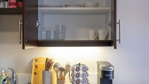 Una cocina con una cafetera, una tabla de cortar y utensilios en la encimera.