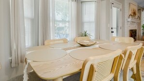 A dining area with a round table and six chairs, a fireplace, and a ceiling light fixture.