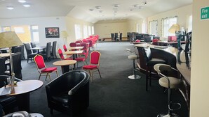 A conference room with tables and chairs, a fire exit sign, and ceiling lights. - Simplystay Lincoln Road (Skegness)