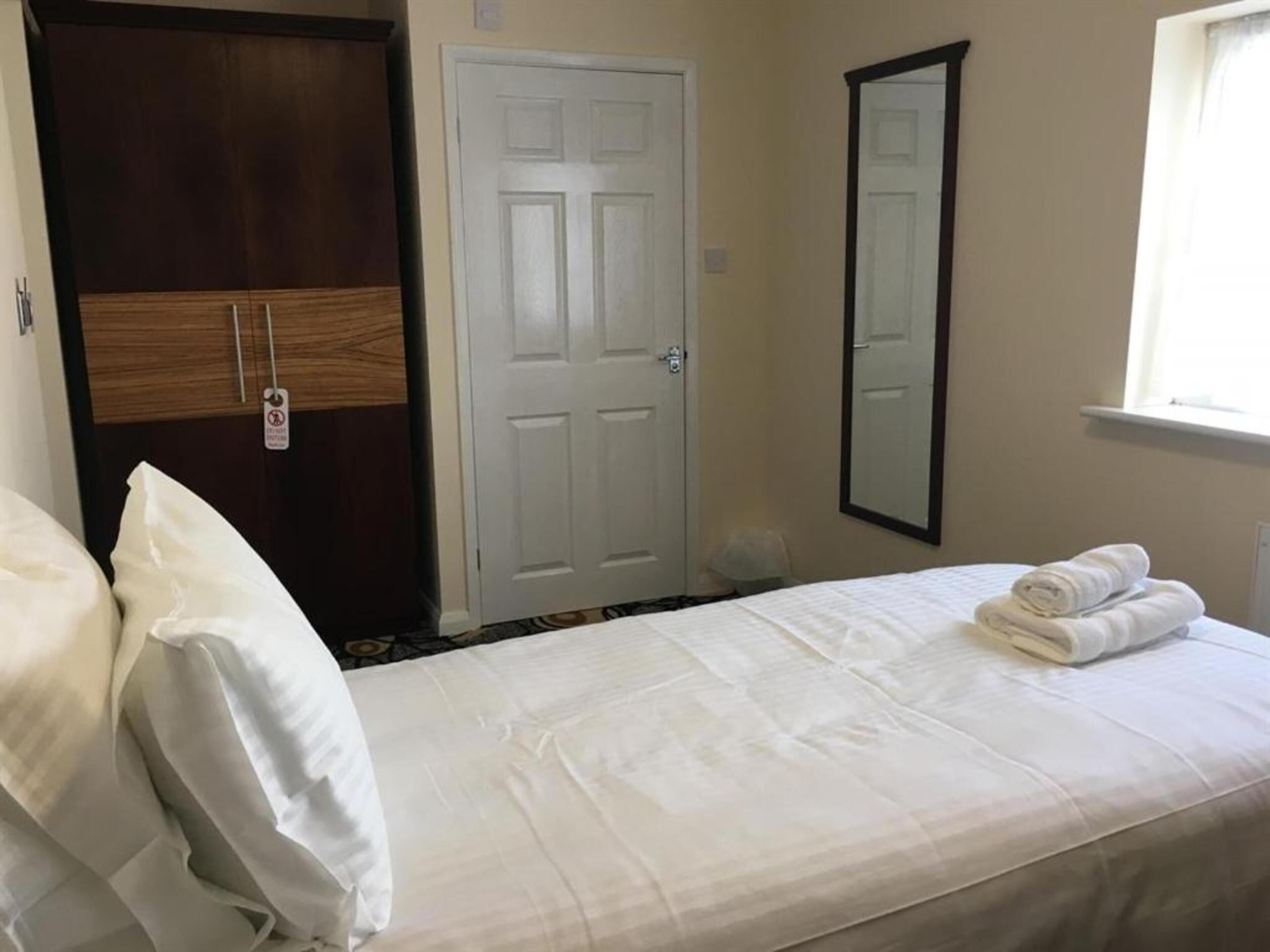 A hotel room with a bed, a wardrobe, a door, and a mirror.