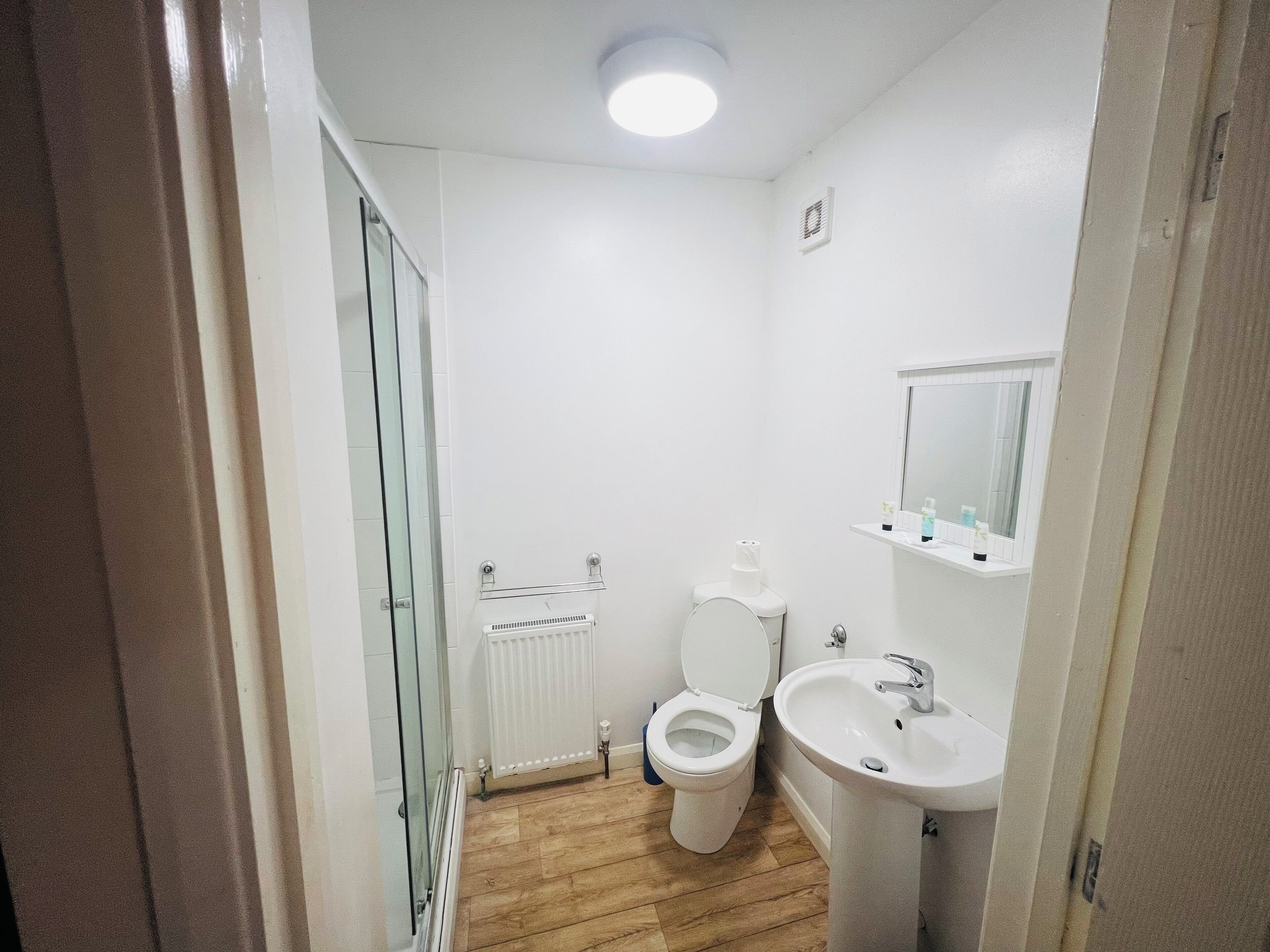 A small, clean bathroom with a toilet, sink, and mirror.