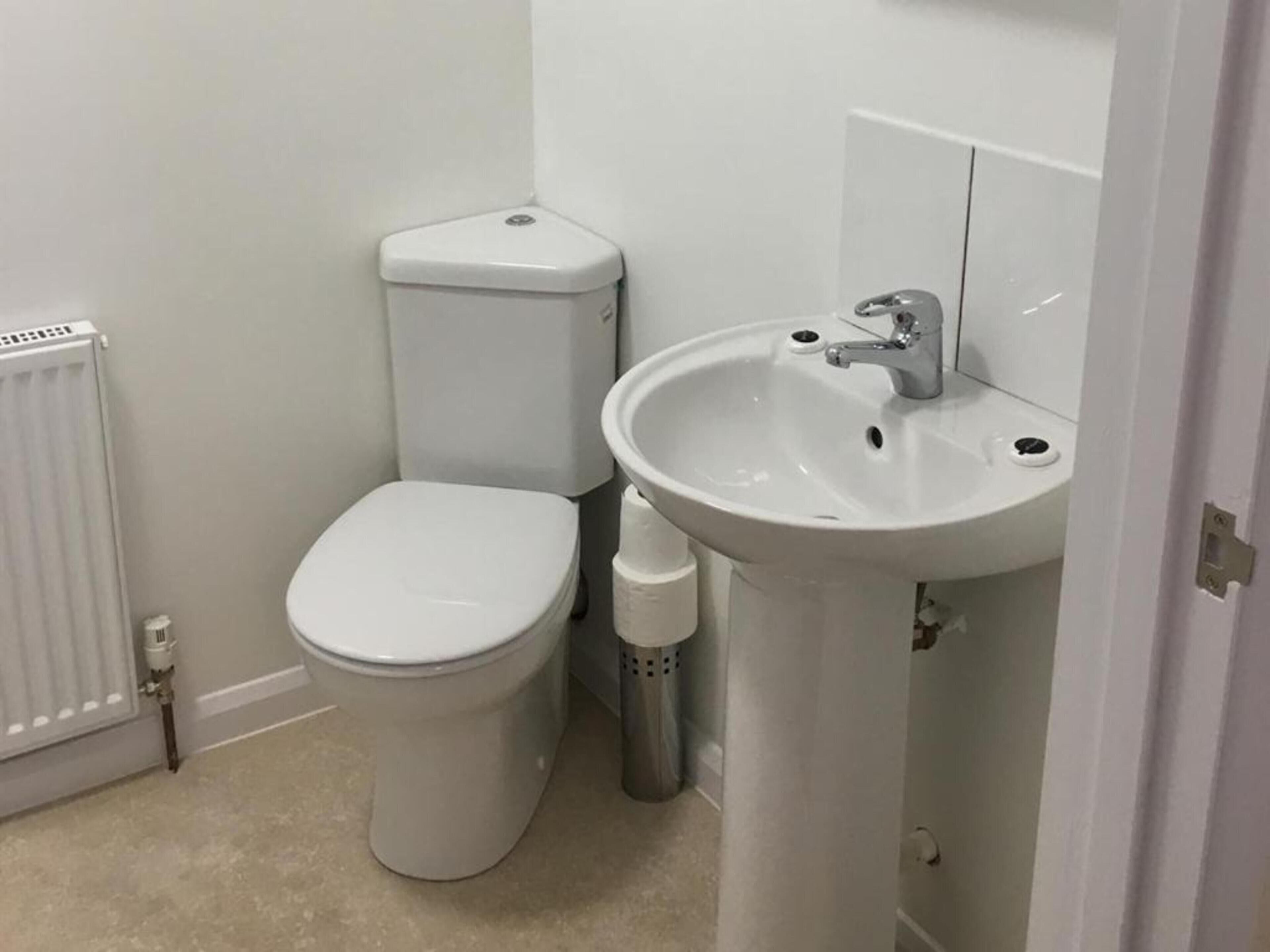 Un baño pequeño y limpio con inodoro, lavabo y radiador.