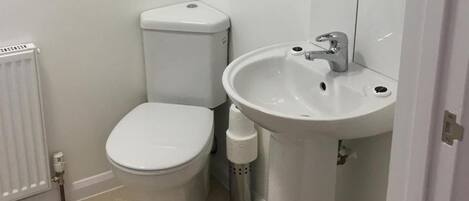 Un baño pequeño y limpio con inodoro, lavabo y radiador.