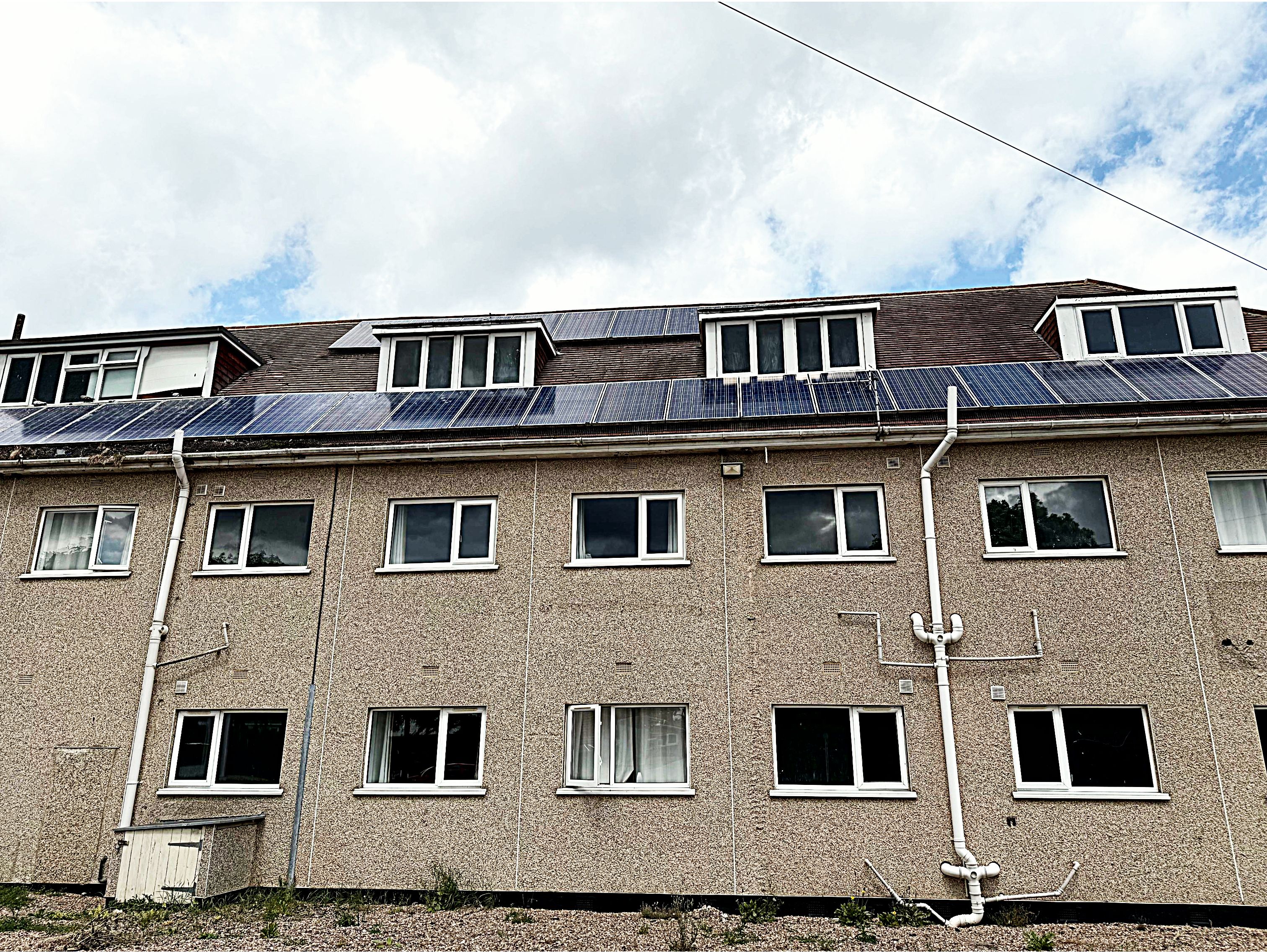 Un immeuble à plusieurs étages, doté d’un toit plat, de nombreuses fenêtres et de tuyaux apparents.