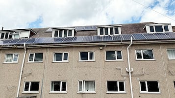 Un immeuble à plusieurs étages, doté d’un toit plat, de nombreuses fenêtres et de tuyaux apparents.