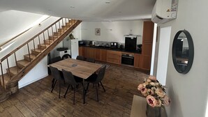 Et moderne køkken med træskabe, et spisebord med stole og en trappe til et andet niveau.