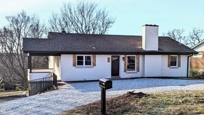 Ein eingeschossiges Haus mit dunklem Dach, weißen Außenwänden und einem Schornstein.