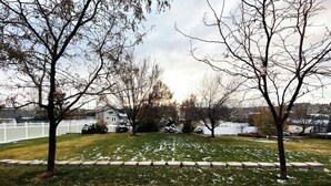 A residential lawn with a white fence, trees, and houses in the background. - Cozy Private Suite with Kitchen, Gym, and More in UT! (Draper)