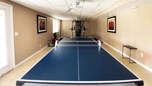 A room with a ping pong table, exercise equipment, and framed pictures on the walls. - Cozy Private Suite with Kitchen, Gym, and More in UT! (Draper)