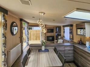 Een moderne keuken met een eethoek, houten vloer, een centrale lamp en uitzicht naar buiten.