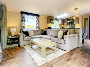 Ein modernes Wohnzimmer mit einer Couch, einem Couchtisch und einer Küche im Hintergrund.