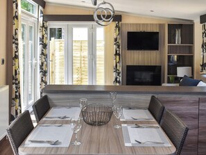 A dining area with a long table, chairs, and a central wine glass.