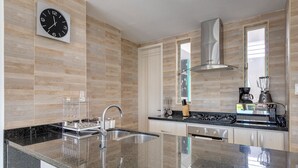 A modern kitchen with a granite countertop, stainless steel appliances, and a clock on the wall. - Luxury Airport Penthouse 4 BD 3 BA + Rooftop Pool

 (Edificio La Frontier)