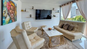 A modern living room with a beige sofa, two armchairs, a coffee table, and a flat-screen TV mounted on the wall. - Luxury Airport Penthouse 4 BD 3 BA + Rooftop Pool

 (Edificio La Frontier)