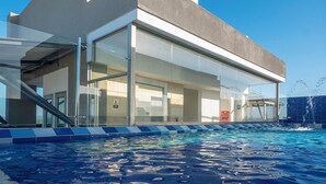A modern building with a glass facade, a pool, and a clear sky. - Luxury Airport Penthouse 4 BD 3 BA + Rooftop Pool

 (Edificio La Frontier)