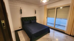 Een slaapkamer met een bed, een raam met zonwering en een deur.