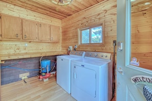 A compact kitchen with wooden walls, a window, and a washing machine. - Lake House - Wisconsin Northwoods - Pets Ok - Open for Hunting/Rifle Season (Gordon)