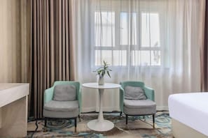 A hotel room with a bed, two chairs, a small table with a plant, and a window with curtains. - Qiyu Hotel (Burqin)