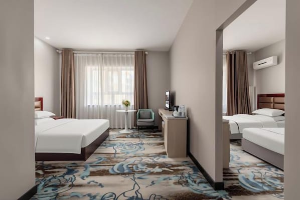 A hotel room with two beds, a desk, a chair, and a television.
