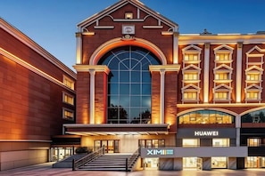 A hotel with a grand entrance, a large arched window, and a sign for Huawei.