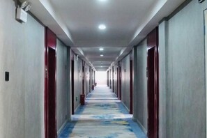 A long hallway with doors on both sides, a patterned carpet, and a ceiling with recessed lighting. - Qiyu Hotel (Burqin)