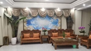 A room with a large painting of clouds and birds, wooden furniture, and potted plants. - Qiyu Hotel (Burqin)