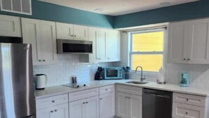 A modern kitchen with white cabinets, a stainless steel refrigerator, a microwave, and a dishwasher.