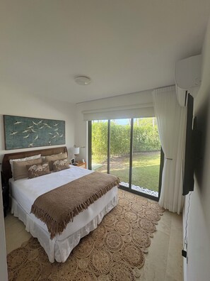 A bedroom with a large bed, a painting of birds, a TV, and a view of the outdoors. - Cheap and Charming 1 bedroom villa with AC, WiFi in fabulous Puerto Plata (Puerto Plata Province)