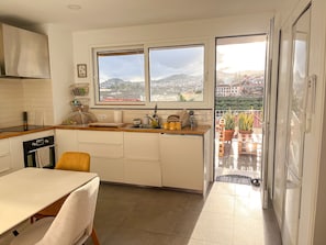 Uma cozinha moderna com uma janela ampla, área de refeições e vista para a paisagem urbana.