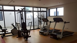 Een sportschool met trainingsapparatuur, grote ramen en uitzicht.