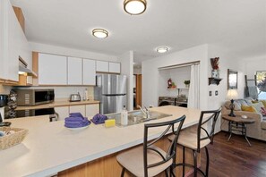 Una cocina moderna con una isla central, electrodomésticos de acero inoxidable y un comedor con taburetes de bar.