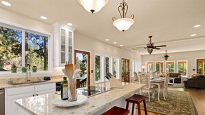 Una cocina amplia con una isla grande, muebles blancos y un comedor con candelabro.