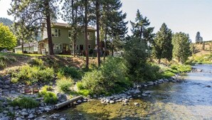 Una casa junto a un río, con una terraza de madera y una silla.