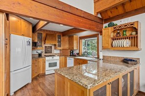 A kitchen with wooden cabinets, a granite countertop, a refrigerator, and a stove.