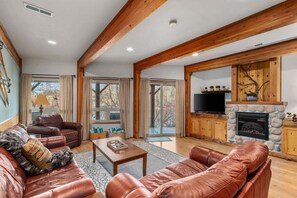 A spacious living room with leather sofas, a fireplace, and a television.