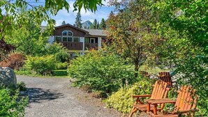 A pathway leading to a building surrounded by lush greenery and wooden chairs. - Leavenworth Condo - 1BR w/ Jetted Tub + Pool (Leavenworth)