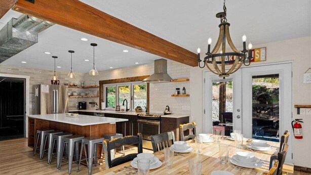Una cocina moderna con una isla central, taburetes de bar y una mesa de comedor preparada para seis personas.