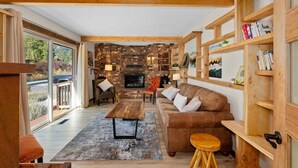 Un salón acogedor con chimenea, estanterías de madera y un ventanal grande.
